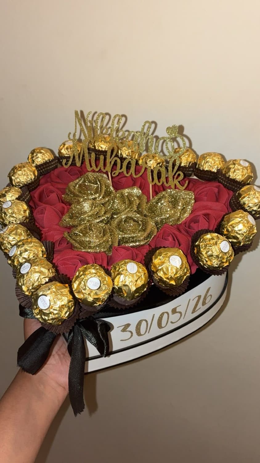 A heart box of deep red roses and gold glitter roses edged with Ferrero Rocher, dated 30/05/26 on the side