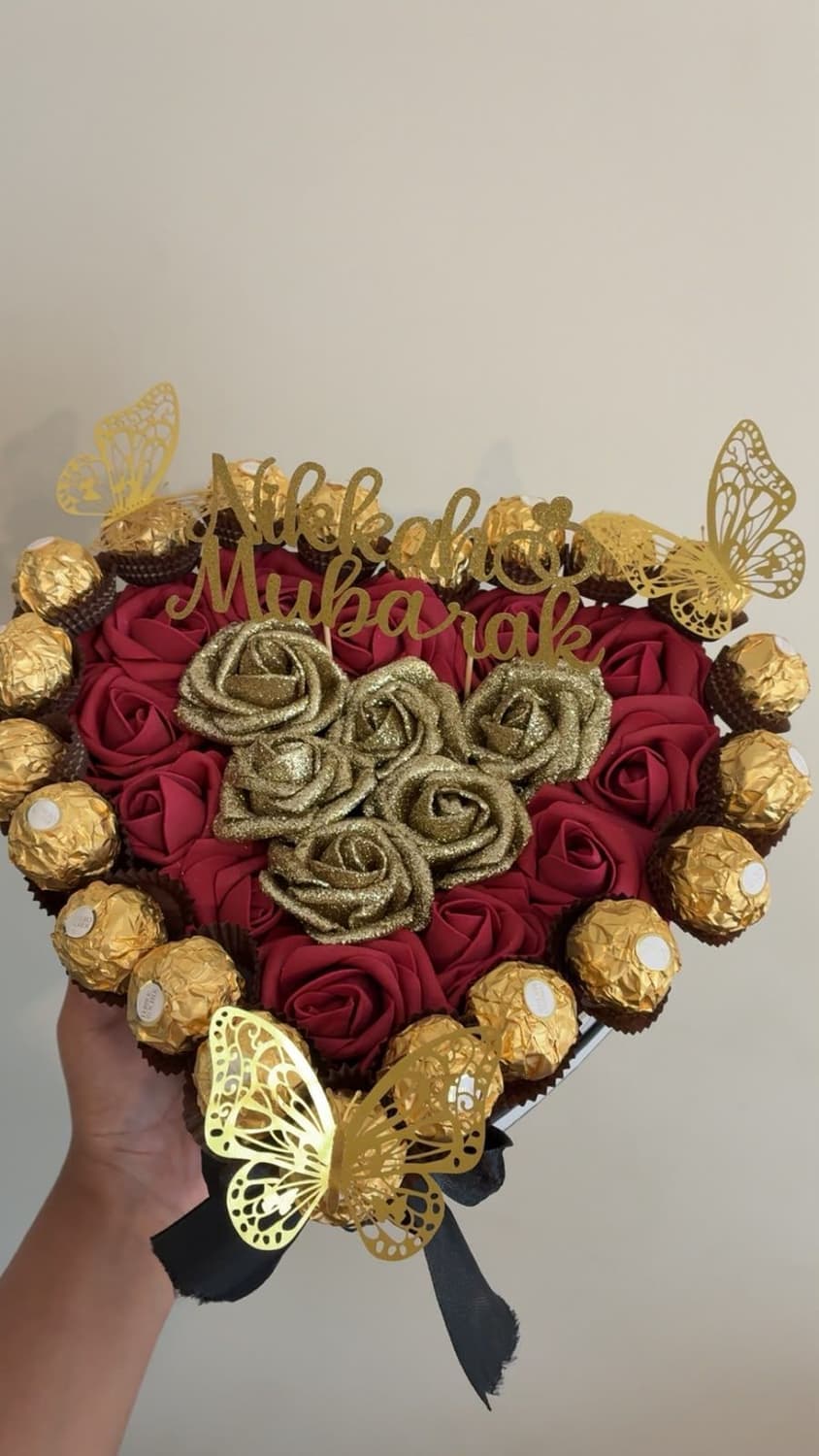 A heart box of red and gold glitter roses edged with Ferrero Rocher, with gold butterflies and a Nikkah Mubarak topper