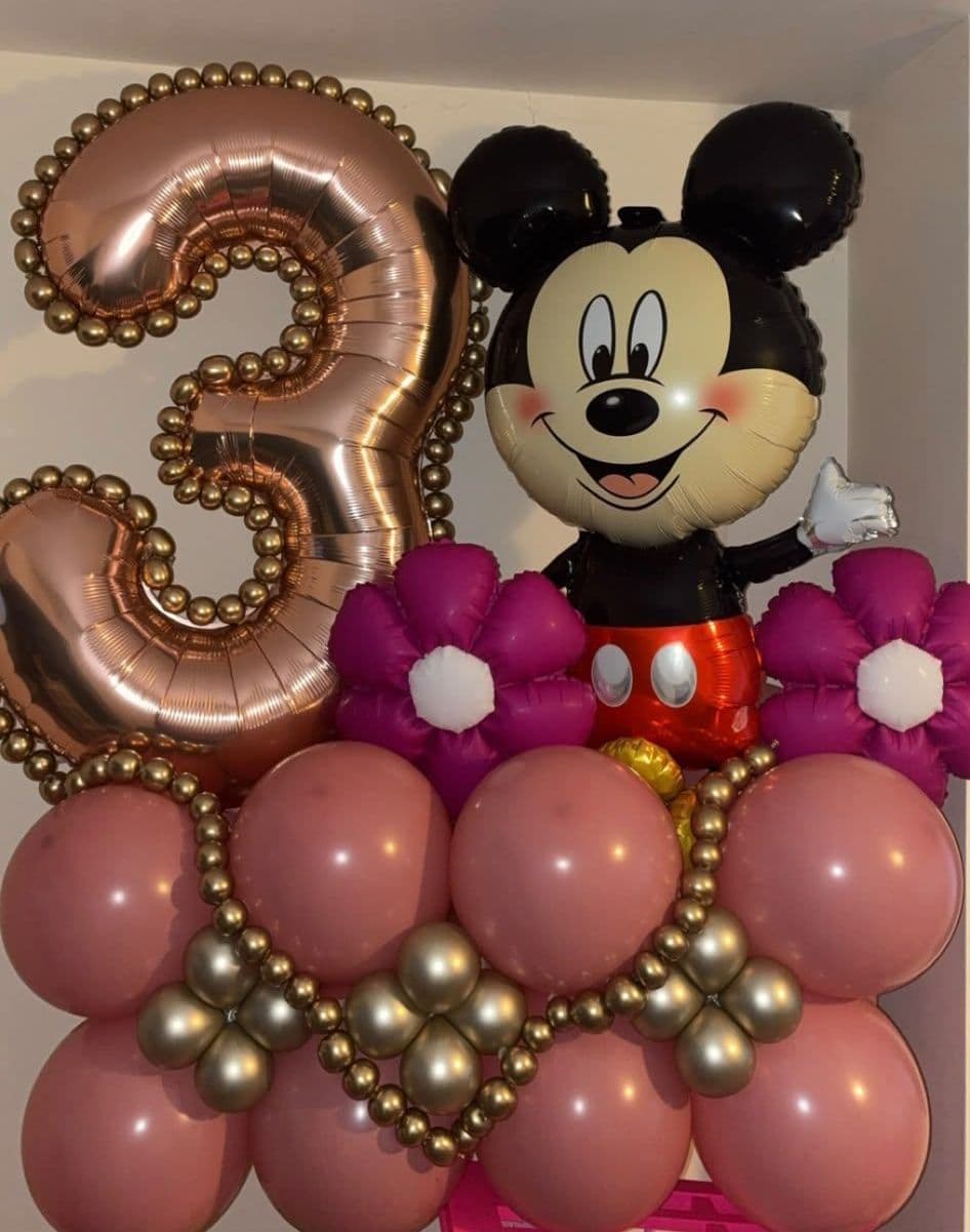 A number three stack close up, with rose gold pearl balloons, pink flowers and a Mickey Mouse foil