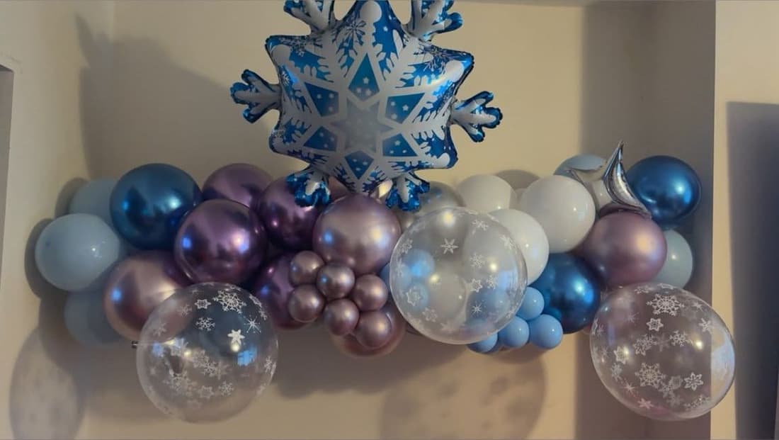 A blue, purple and white balloon garland with a snowflake foil and clear snowflake-print balloons